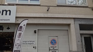 A multi-story building with a brick facade, multiple windows, and a garage door with a sign indicating no parking. - Two bedrooms apartment with free underground parking place (Etterbeek)