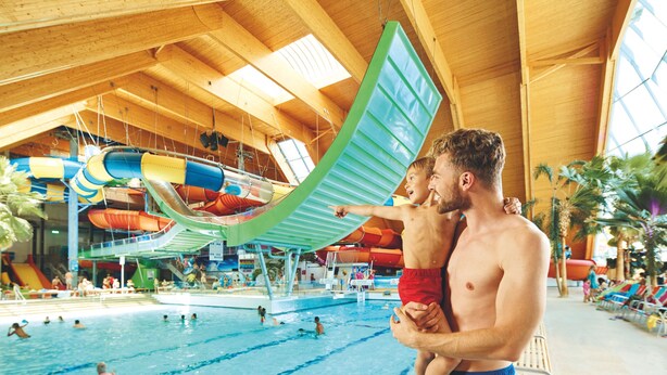 Ein Hallenbad mit mehreren Bahnen und einer Wasserrutsche.