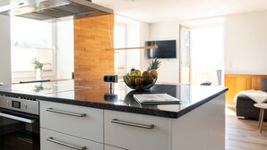 Eine moderne Küche mit weißen Schränken, einer Arbeitsplatte aus Granit und einer Obstschale.