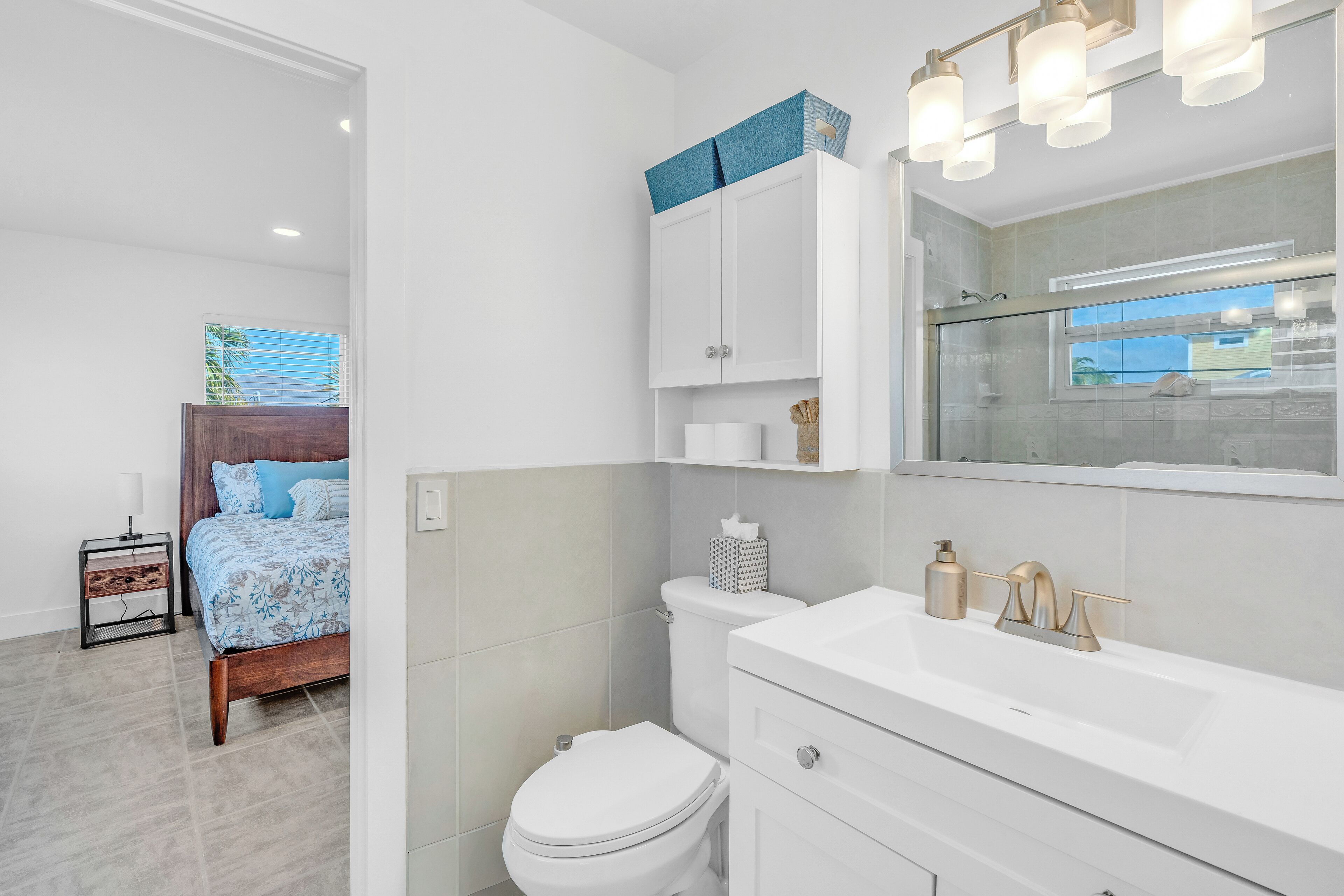 Un baño moderno con un lavamanos blanco, grifería dorada y una cabina de ducha de vidrio.