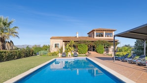 Une piscine avec des chaises longues et une maison avec un toit en tuiles.