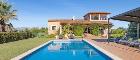 Una piscina con sillas de descanso y una casa con techo de tejas.