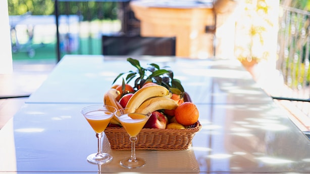 Une table avec un panier de fruits et deux verres à martini.