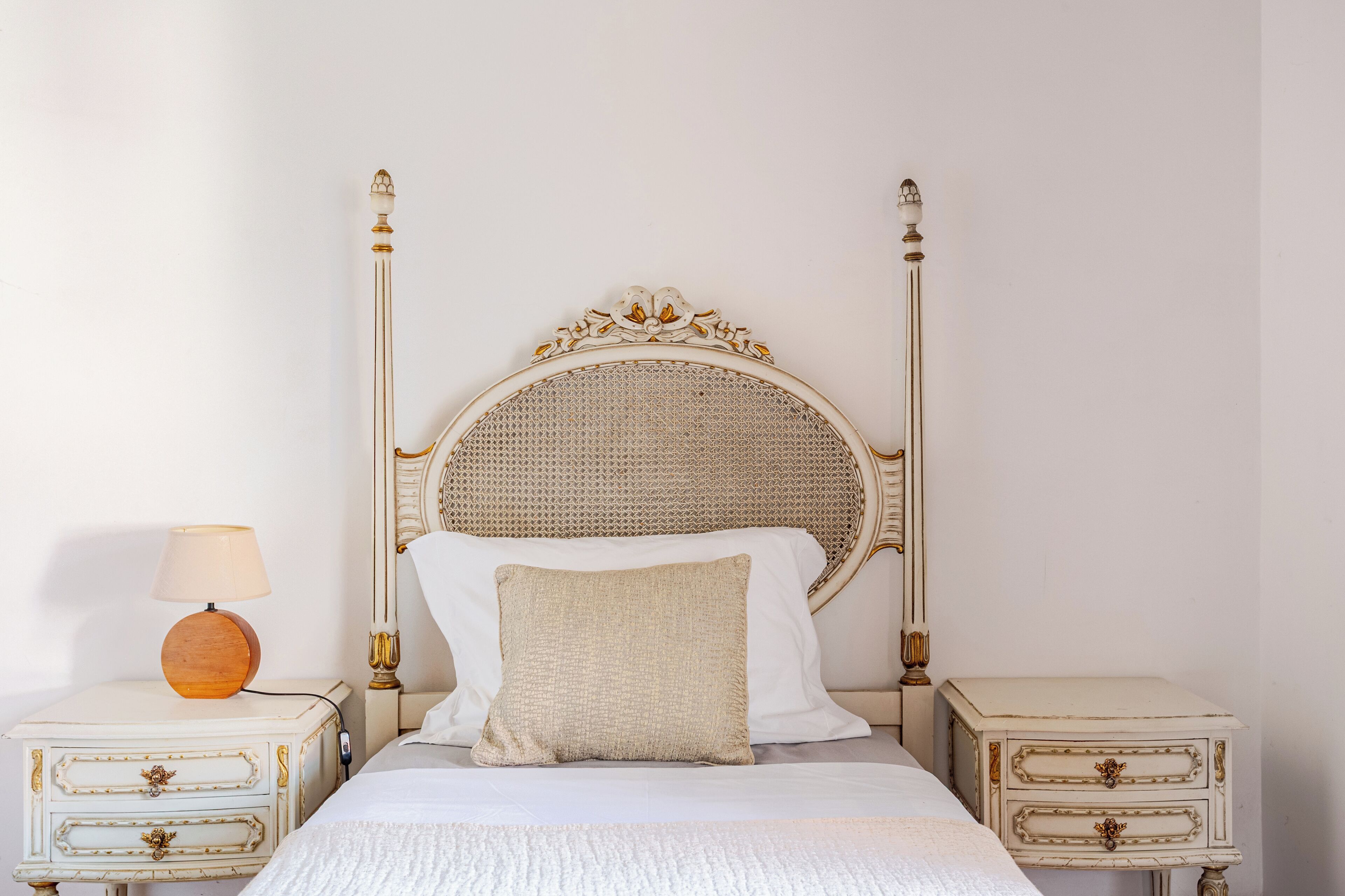 A bed with a round headboard, two bedside tables with drawers, and a lamp on one of the tables.