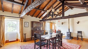 Un comedor con mesa de madera, sillas, una lámpara de araña y un tapete estampado.