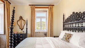 Un dormitorio con una cama con dosel, un aparador, un espejo y una ventana con cortinas.