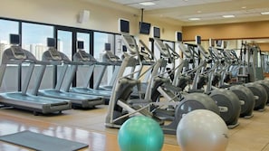 A gym with multiple treadmills and elliptical machines, a green exercise ball, and a yoga mat. - Waikiki 1BR Retreat at Kalia Suites – Full Kitchen, Walk to Beach & Ala Moana (Honolulu)