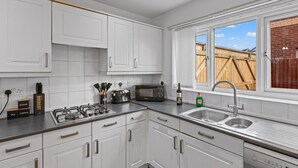 Une cuisine moderne avec des meubles blancs, une cuisinière à gaz, un four à micro-ondes et un évier.
