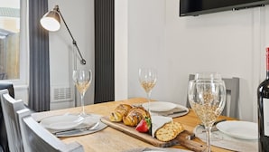 A dining table set with plates, cutlery, glasses, and a bottle of wine. - The Crews Quarters Anfield - Sleeps 10 - Modern (Merseyside)