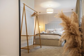 Un dormitorio con una cama, un perchero de madera, una lámpara colgante y una planta grande en maceta.