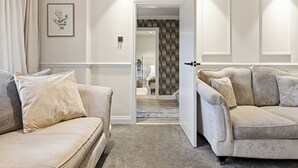 A modern living room with two beige sofas, a framed floral artwork, and a patterned wall.