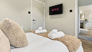 A hotel room with a bed, a television mounted on the wall, and a door.