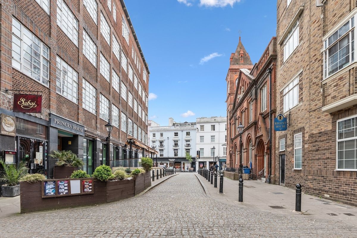 A cobblestone street lined with historic brick buildings, including a Princes House and a Regent House.