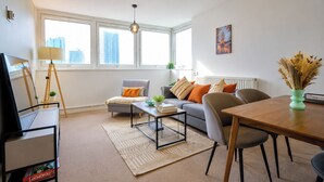 Una sala de estar moderna con un sofá, una mesa de centro, una mesa de comedor y un televisor sobre un mueble.