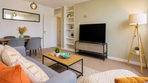 Un salón con sofá, mesa de centro, televisor y lámpara.