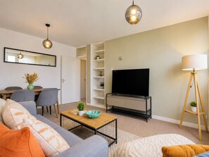 A living room with a sofa, coffee table, TV, and a lamp. - Stylish 2 Bed Flat Near Old Street (Greater London)