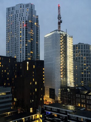 A cityscape with modern high-rise buildings, including a prominent rectangular building with a crane on top. - Stylish 2 Bed Flat Near Old Street (Greater London)