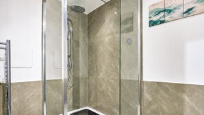 Ducha envuelta en vidrio con ducha de mano y grifo empotrado.