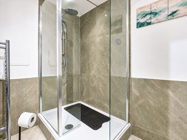 A glass-enclosed shower with a handheld showerhead, a handheld showerhead, and a wall-mounted faucet. - Stylish 2 Bed Flat Near Old Street (Greater London)