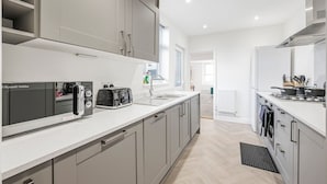 A modern kitchen with grey cabinets, a white countertop, and a built-in oven.
