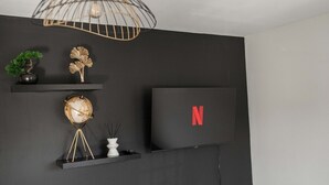 Un saló modern amb una paret negra, un glob terràqui sobre un suport, el logotip de Netflix i una làmpada decorativa.