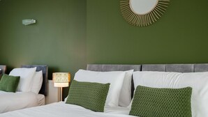 Una habitació d'hotel amb un llit, una tauleta de nit, una làmpada i un mirall fixat a la paret.