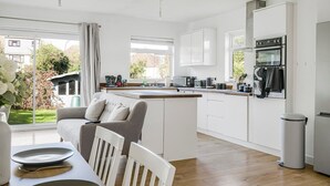 A modern kitchen with white cabinetry, a central island, and a dining area with a table and chairs.