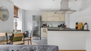 Une cuisine moderne dotée d’un îlot central, d’appareils électroménagers en acier inoxydable et d’un design minimaliste.