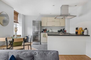 A modern kitchen with a central island, stainless steel appliances, and a minimalist design. - Chelmsford City Flat I Secure Parking I Sleeps 4 (Essex)