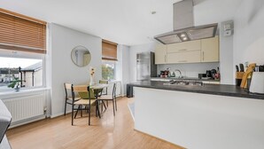 Une cuisine moderne dotée d’un îlot central, d’un coin repas avec une table et des chaises, et offrant une vue par la fenêtre.