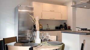 Une cuisine moderne avec une table à manger pour quatre personnes, des appareils en acier inoxydable et des meubles de couleur claire.