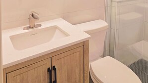 A bathroom with a toilet, sink, and shower. - Boutique Hotel - King Room - Far Out Motel (Starkville)