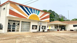 A building with a large garage door and a sunburst mural on the facade.