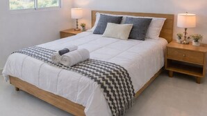 Een keurig opgemaakt slaapkamer met een groot bed, twee nachtkastjes en een raam.