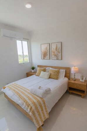 A bedroom with a bed, bedside tables, a lamp, and two wall-mounted paintings. - Santiago-Tu Espacio Perfecto con Vista y Comodidad (Sabaneta las palomas)
