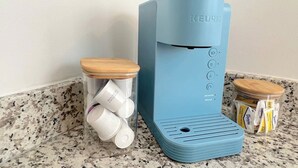 Une machine à café Keurig avec une base bleue, un réservoir d’eau et un compartiment pour les dosettes de café.