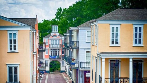 A narrow street lined with multi-story buildings, featuring balconies and a central archway.