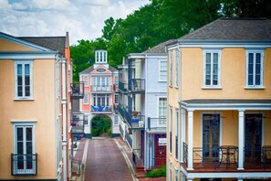 A narrow street lined with multi-story buildings, featuring balconies and a central archway. - The Bulldog Basecamp | Sleeps 18 | Game Day (Starkville)