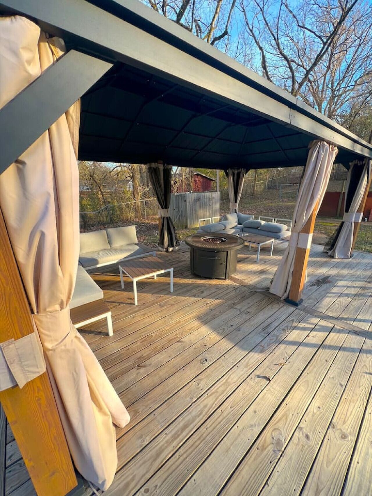 A wooden deck with outdoor seating, including a fire pit and lounge chairs.