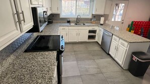 A kitchen with white cabinets, a black stove, and a granite countertop.