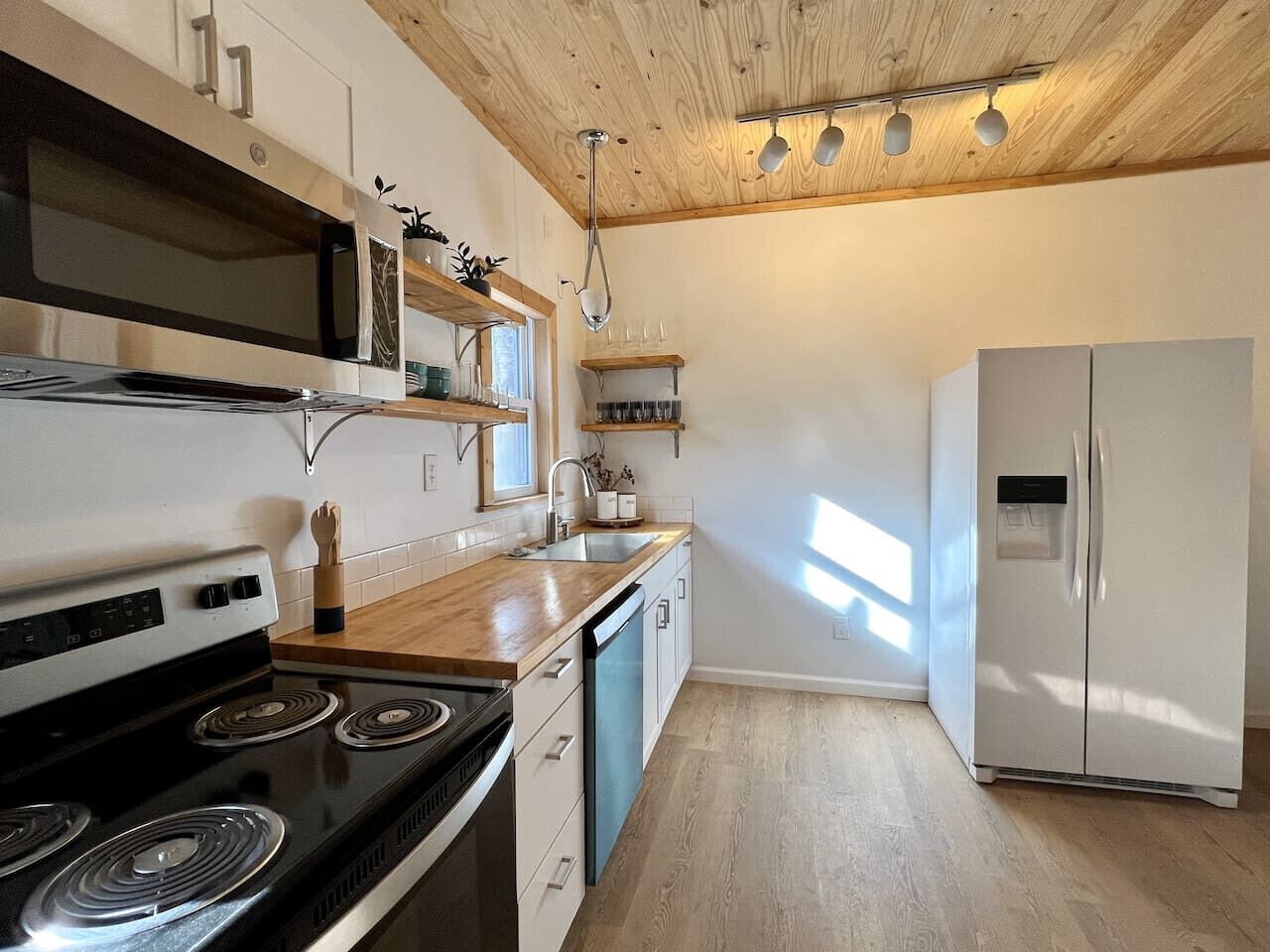 A kitchen with a stove, oven, microwave, and refrigerator. There are wooden cabinets and a countertop.