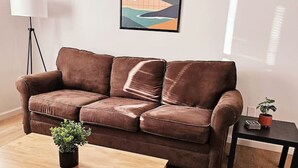 A brown leather sofa with a wooden coffee table and a small plant. - Cozy 2-Bedroom Haven: Sleeps 5! (Starkville)
