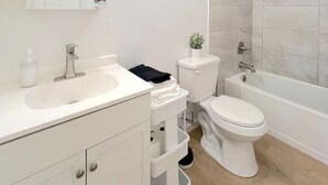 Une salle de bain moderne avec un meuble-lavabo blanc, des toilettes, une baignoire et une douche.