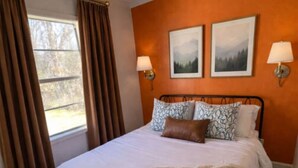 Une chambre à coucher avec un grand lit, deux lampes fixées au mur et deux tableaux encadrés.