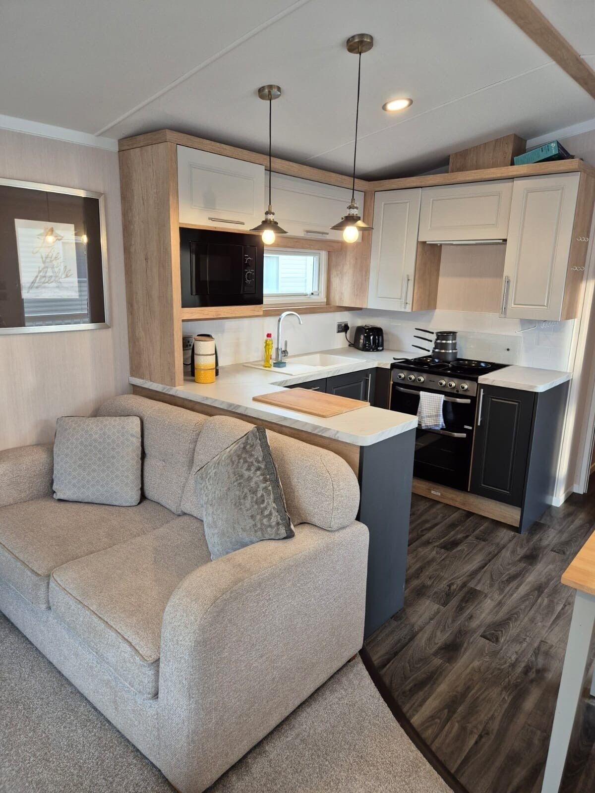 A compact kitchen with a central island, a built-in microwave, a stove, and pendant lighting.