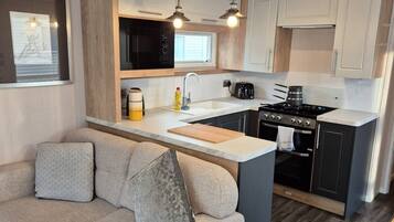 A compact kitchen with a central island, a built-in microwave, a stove, and pendant lighting.