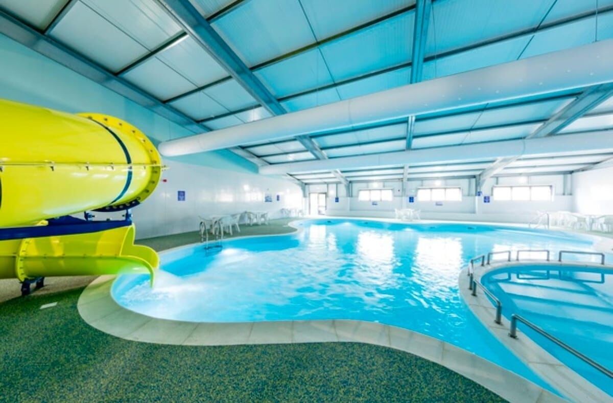 An indoor swimming pool with a yellow water slide and a clear blue pool.