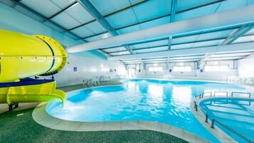 An indoor swimming pool with a yellow water slide and a clear blue pool.