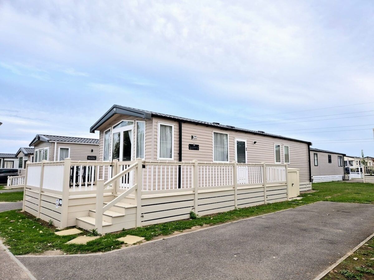A single-story mobile home with a front porch and a fenced yard.