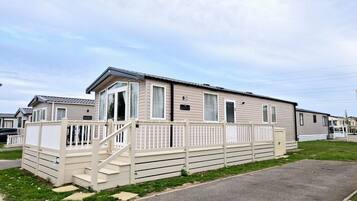 A single-story mobile home with a front porch and a fenced yard.